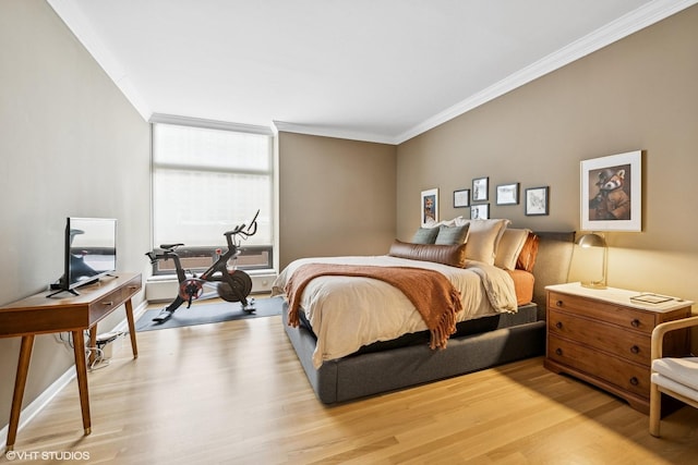 bedroom featuring crown molding, light wood-style floors, and baseboards