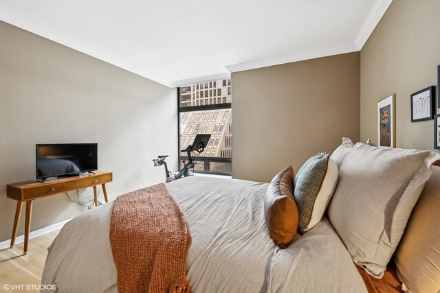 bedroom featuring crown molding, light wood-style floors, and baseboards