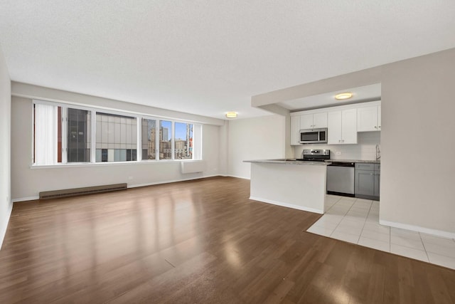 801 S Plymouth Ct Unit 711, Chicago, IL 60605 - kitchen featuring appliances with stainless steel finishes, light wood-type flooring, open floor plan, baseboards, and white cabinets