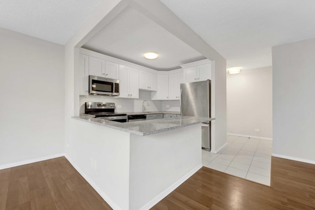 801 S Plymouth Ct Unit 711, Chicago, IL 60605 - kitchen with stainless steel appliances, light wood-style flooring, a peninsula, white cabinets, and light stone countertops