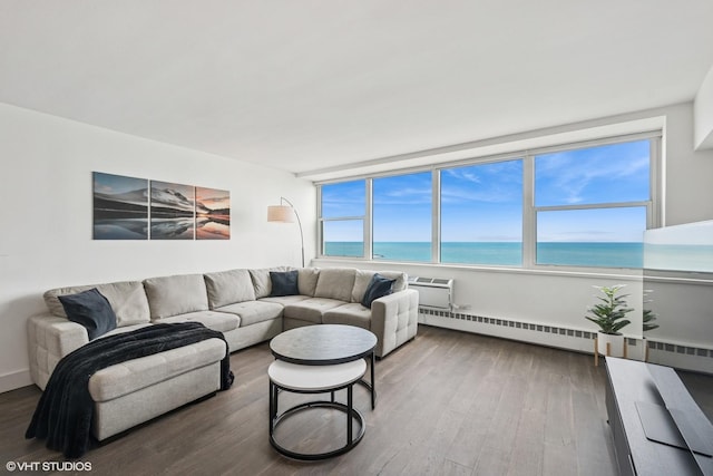 living area featuring wood finished floors, baseboard heating, a water view, and an AC wall unit