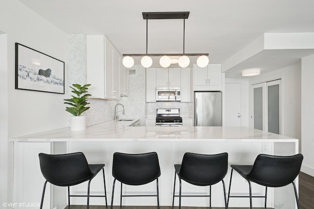 kitchen featuring appliances with stainless steel finishes, a peninsula, light countertops, backsplash, and a breakfast bar