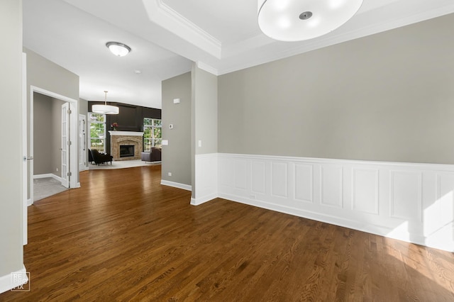 11911 Winterberry Ln, Plainfield, IL 60585 - empty room featuring dark wood-style flooring, a stone fireplace, crown molding, and baseboards