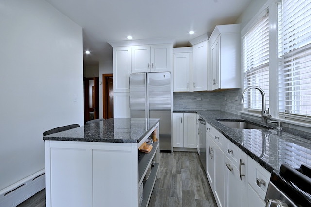 6211 W School St, Chicago, IL 60634 - kitchen featuring a baseboard heating unit, stainless steel appliances, a sink, wood finished floors, and white cabinetry