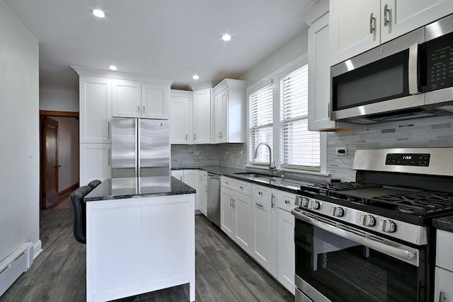 6211 W School St, Chicago, IL 60634 - kitchen featuring appliances with stainless steel finishes, a sink, a baseboard heating unit, a center island, and dark stone counters