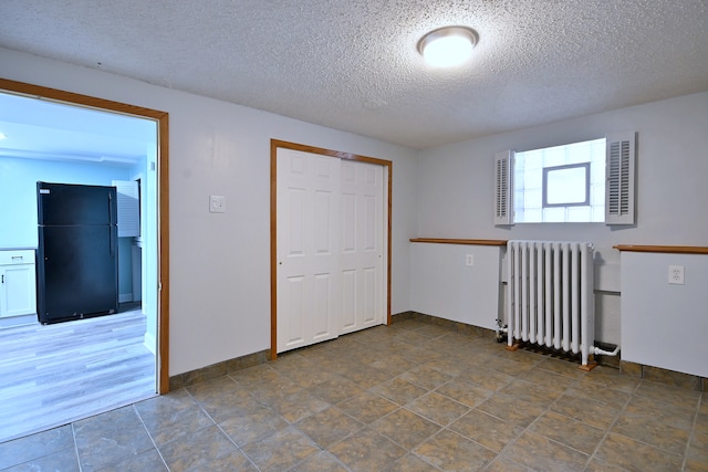 6211 W School St, Chicago, IL 60634 - spare room featuring radiator heating unit, a textured ceiling, and baseboards