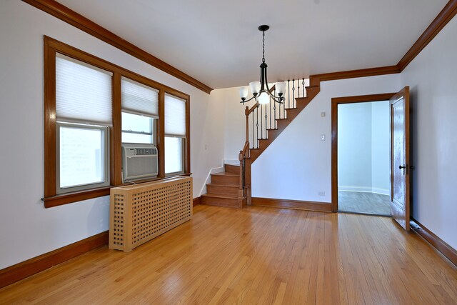 6211 W School St, Chicago, IL 60634 - empty room featuring a chandelier, radiator heating unit, stairway, baseboards, and crown molding