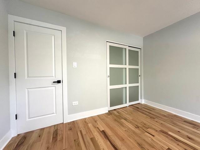 unfurnished bedroom featuring light wood-style floors, baseboards, and a closet