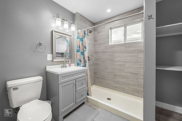 bathroom featuring a tile shower, toilet, and vanity