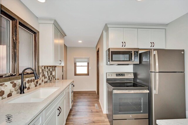 2958 N 1100 E Rd, Clifton, IL 60927 - kitchen featuring stainless steel appliances, a sink, light stone counters, light wood-style flooring, and backsplash