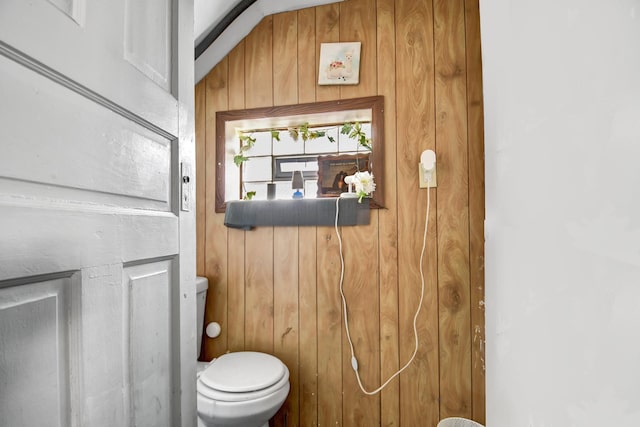 bathroom featuring wood walls and toilet