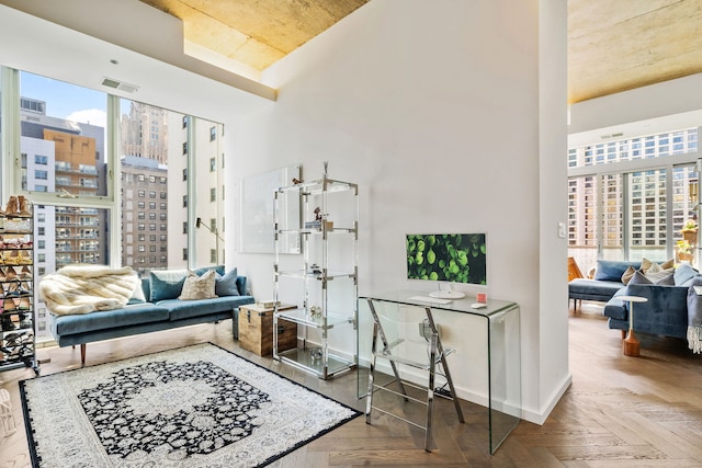 living area featuring plenty of natural light, a high ceiling, a city view, and baseboards
