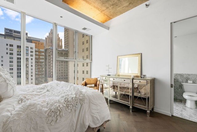 bedroom featuring a city view, baseboards, and connected bathroom