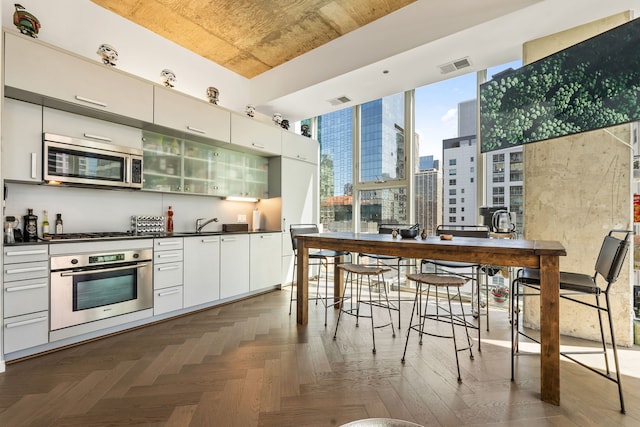 kitchen with appliances with stainless steel finishes, dark countertops, a view of city, modern cabinets, and white cabinets