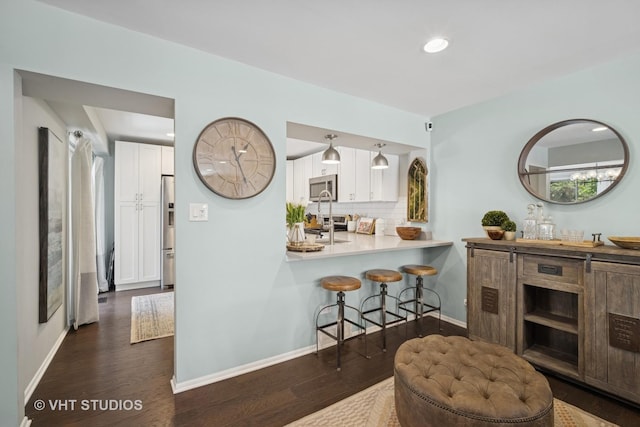 921 Harlem Ave Unit 1, Glenview, IL 60025 - kitchen featuring appliances with stainless steel finishes, a breakfast bar, white cabinets, tasteful backsplash, and recessed lighting