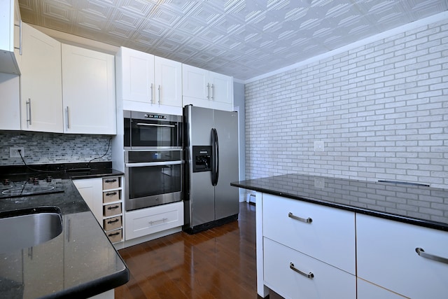 kitchen featuring appliances with stainless steel finishes, an ornate ceiling, dark wood-style floors, backsplash, and dark stone countertops