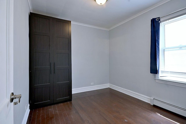 unfurnished room featuring a baseboard radiator, dark wood-style floors, baseboards, healthy amount of natural light, and ornamental molding
