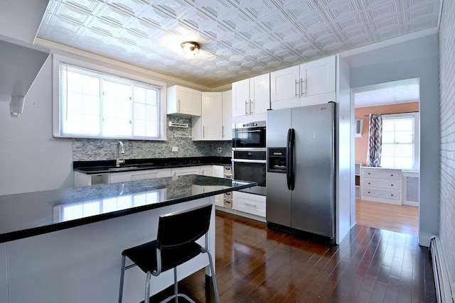 kitchen with stainless steel appliances, a baseboard radiator, an ornate ceiling, a sink, and dark countertops