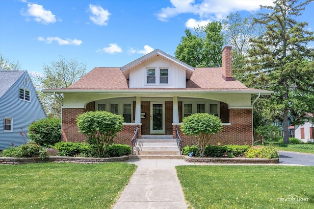 bungalow-style house featuring brick siding, a front lawn, a chimney, and covered porch