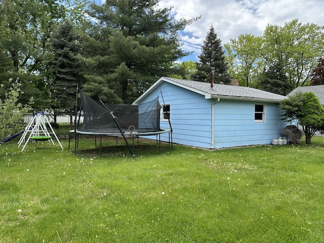 758 Edwin Dr, Bourbonnais, IL 60914 - back of property featuring a trampoline, roof with shingles, a chimney, and view of wooded area