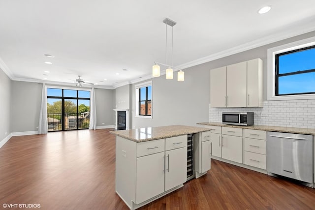 kitchen with appliances with stainless steel finishes, a fireplace, crown molding, decorative backsplash, and a center island
