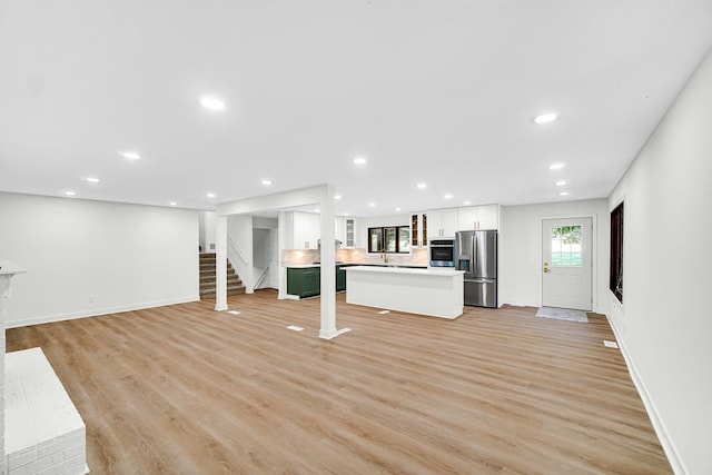 unfurnished living room featuring stairs, light wood-style flooring, baseboards, and recessed lighting