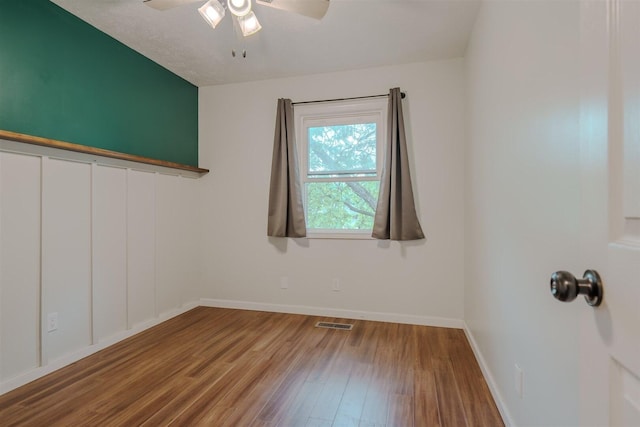 empty room featuring wood finished floors, a ceiling fan, and baseboards