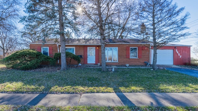 single story home featuring an attached garage, brick siding, a front yard, and driveway