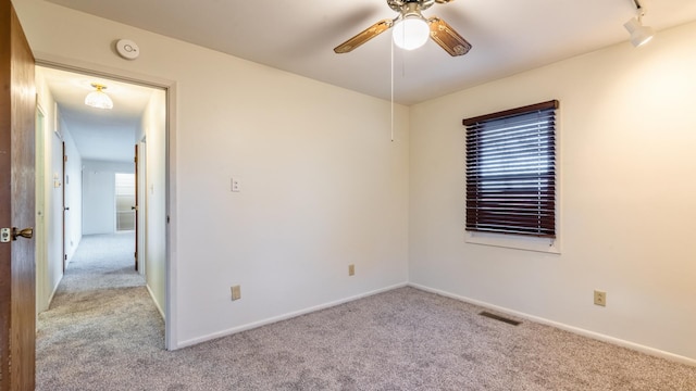 carpeted empty room with a ceiling fan, baseboards, and a smoke detector