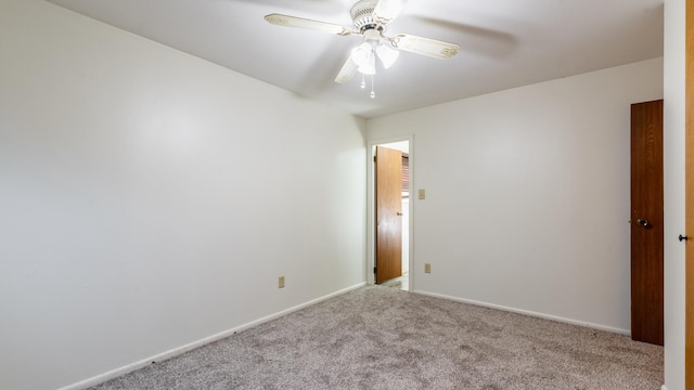 carpeted empty room featuring a ceiling fan and baseboards