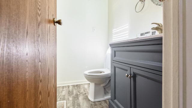 bathroom featuring toilet, wood finished floors, baseboards, and vanity
