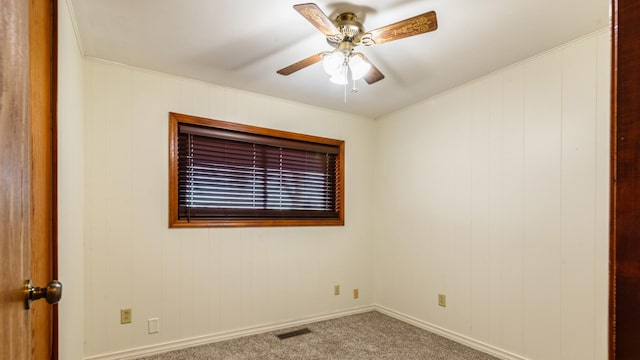 carpeted empty room with ceiling fan, baseboards, and ornamental molding