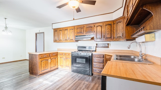 kitchen featuring range with gas stovetop, under cabinet range hood, a peninsula, a sink, and light wood-type flooring