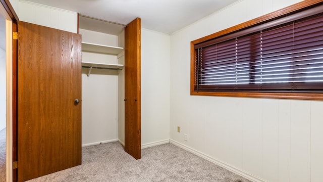 unfurnished bedroom with carpet flooring, a closet, crown molding, and baseboards