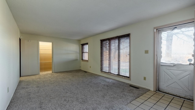 foyer featuring light colored carpet and baseboards