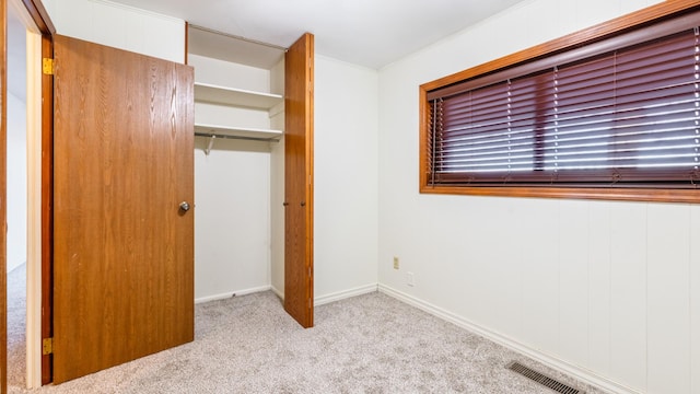 unfurnished bedroom featuring carpet flooring, a closet, crown molding, and baseboards