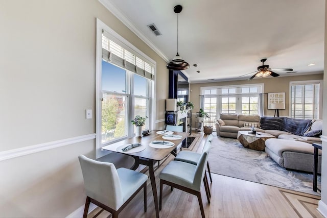 dining space featuring crown molding, wood finished floors, and ceiling fan