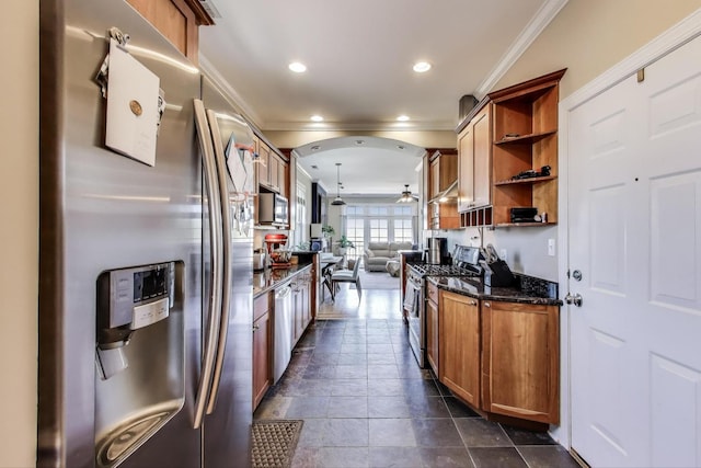 kitchen featuring appliances with stainless steel finishes, ornamental molding, open shelves, brown cabinets, and dark stone countertops