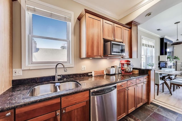 kitchen featuring appliances with stainless steel finishes, a sink, ornamental molding, dark stone countertops, and pendant lighting