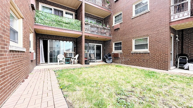 rear view of house featuring brick siding, a balcony, and a patio area