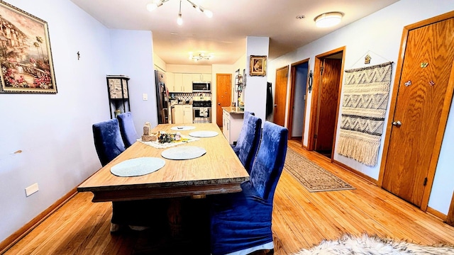 dining area featuring light wood-style floors, baseboards, and a chandelier