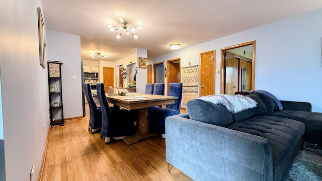 dining room featuring light wood finished floors, a chandelier, and baseboards