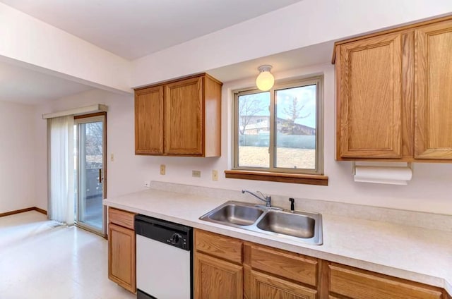kitchen featuring dishwasher, a sink, light countertops, and healthy amount of natural light