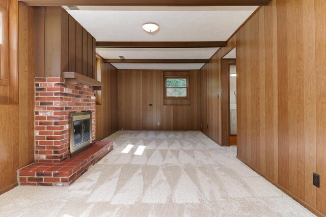 311 Hillside Ln, Bloomington, IL 61701 - unfurnished living room featuring beam ceiling, wood walls, light colored carpet, and a brick fireplace
