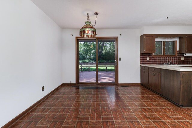311 Hillside Ln, Bloomington, IL 61701 - kitchen with brick patterned floors, baseboards, light countertops, backsplash, and dark brown cabinetry