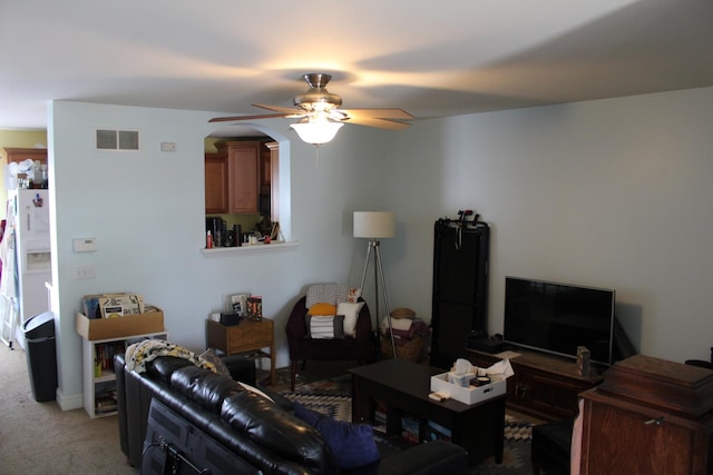 living area with carpet flooring, ceiling fan, and arched walkways