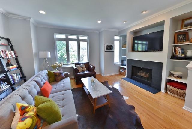 living area with a fireplace with flush hearth, wood finished floors, recessed lighting, ornamental molding, and baseboards