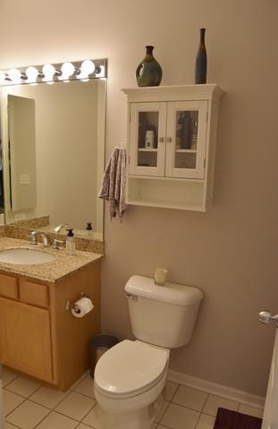 half bathroom featuring tile patterned flooring, toilet, and vanity