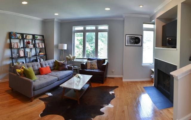 living room featuring healthy amount of natural light, light wood finished floors, baseboards, crown molding, and recessed lighting