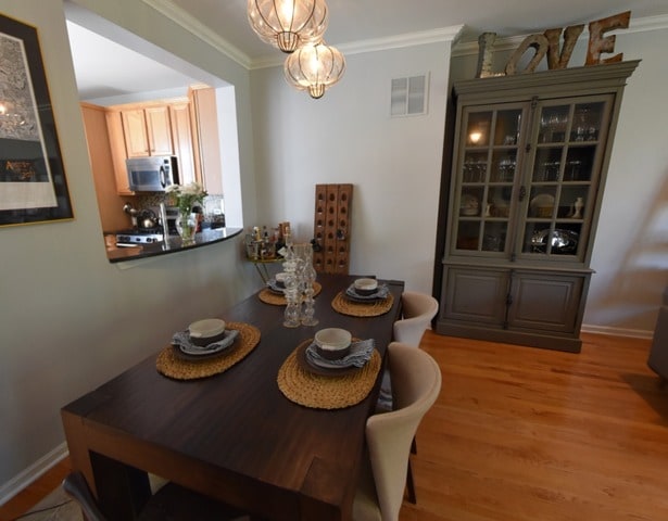 dining space with ornamental molding, light wood finished floors, and a chandelier
